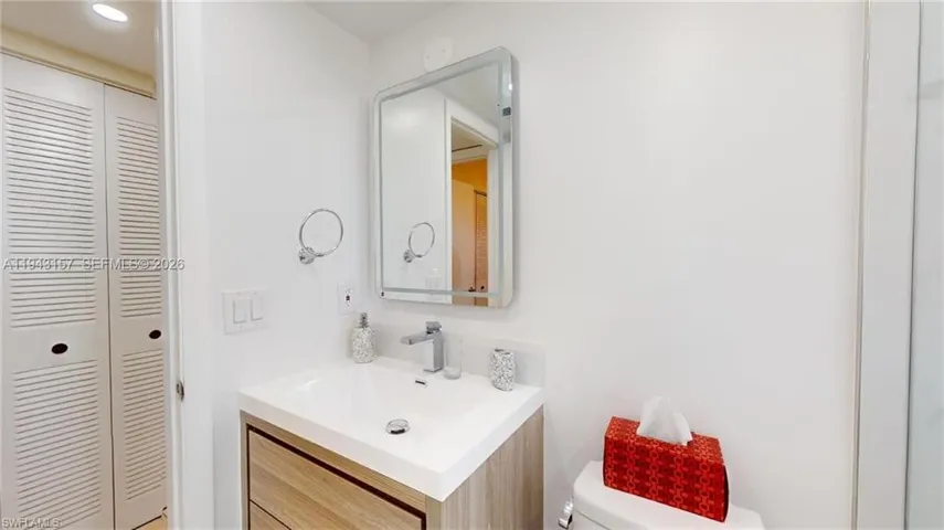 Modern vanity featuring a wood-finish base and integrated white sink with chrome faucet