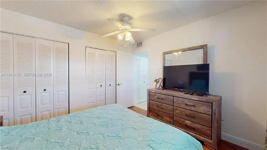 Bedroom with two sets of louvered bi-fold closet doors, a ceiling fan with integrated lighting, and wood-finish flooring