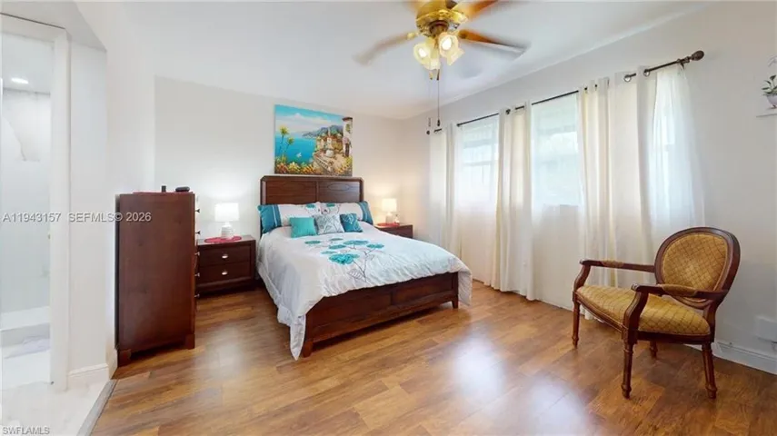 Spacious interior featuring wood-finish flooring, white walls, and a ceiling fan with integrated lighting