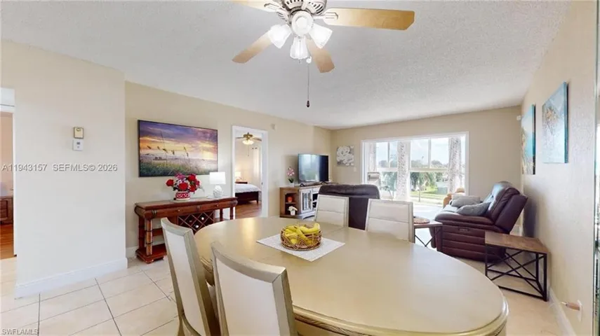 Open concept dining and living area featuring tile flooring, a ceiling fan, and large windows