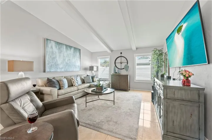 Tiled living room with vaulted ceiling with beams