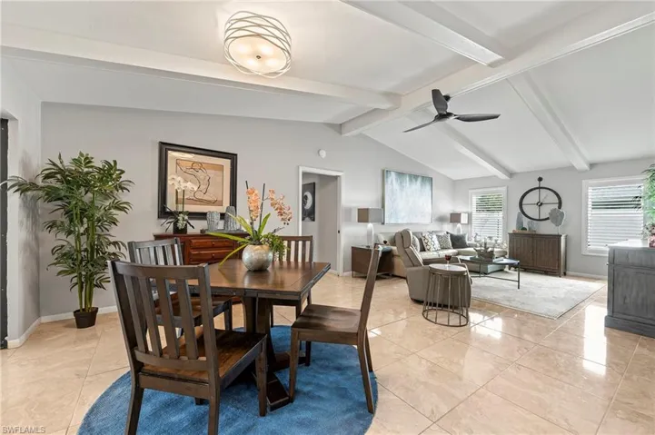 Dining area with lofted ceiling with beams, ceiling fan, and light tile patterned flooring