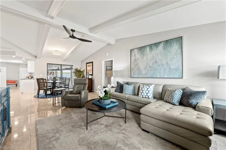 Tiled living room with lofted ceiling with beams and ceiling fan