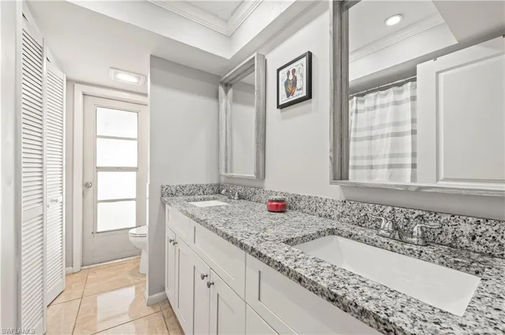 Bathroom with tile patterned floors, vanity, toilet, and crown molding