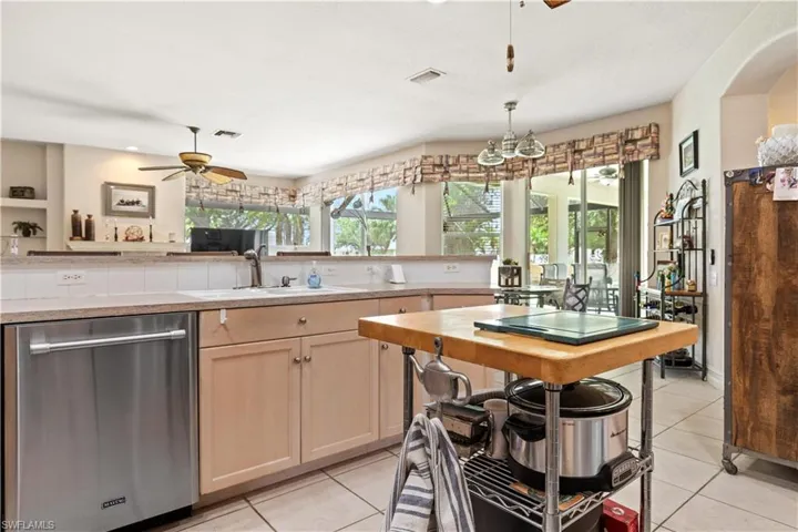 Kitchen featuring ceiling fan, sink, dishwasher, and light tile floors