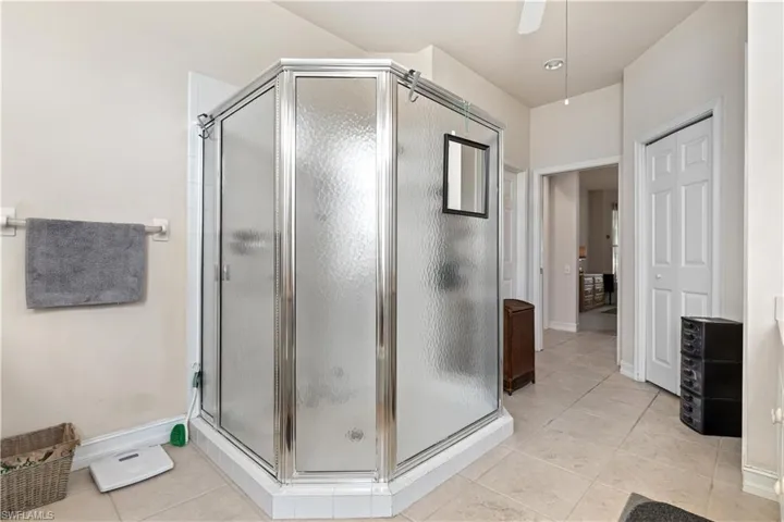 Bathroom featuring a shower with door, tile flooring, and ceiling fan