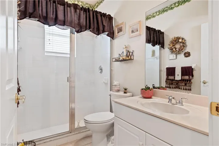 Bathroom with a shower with door, vanity, and toilet
