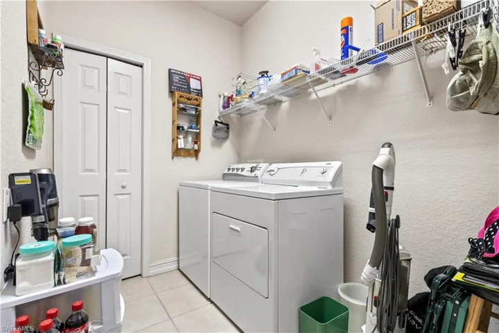 Clothes washing area with washer and clothes dryer and light tile floors