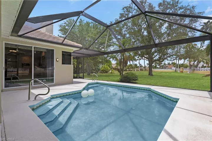 View of swimming pool with a lawn, glass enclosure, and a patio
