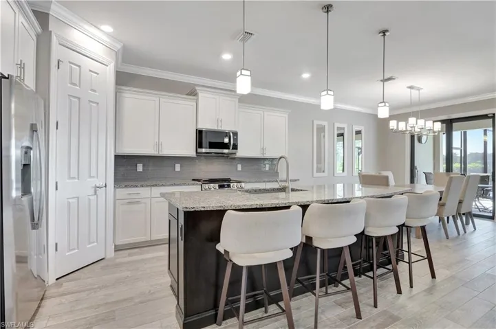 Kitchen with stainless steel appliances, white cabinets, and a kitchen island with sink