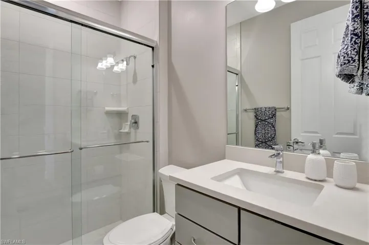 Bathroom featuring vanity, toilet, and a shower with door