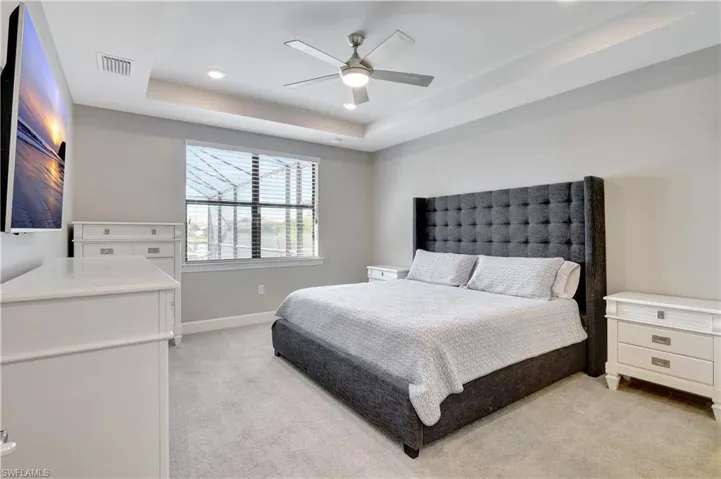 Carpeted bedroom with ceiling fan and a tray ceiling