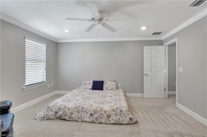 Carpeted bedroom featuring ceiling fan and crown molding