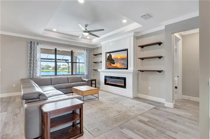Living room featuring crown molding, ceiling fan, a tray ceiling, and light hardwood / wood-style floors
