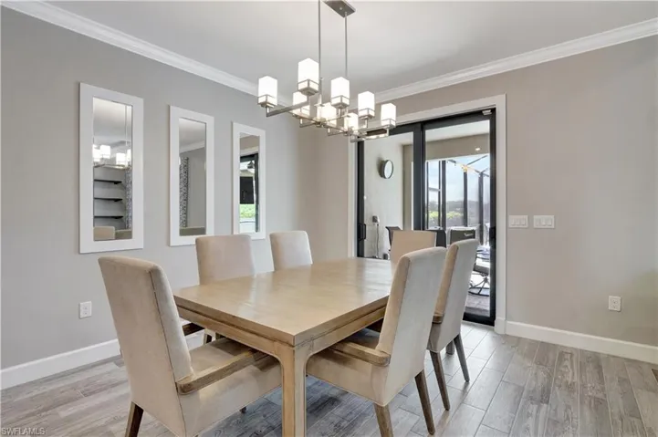 Dining area with light hardwood / wood-style flooring, ornamental molding, and an inviting chandelier