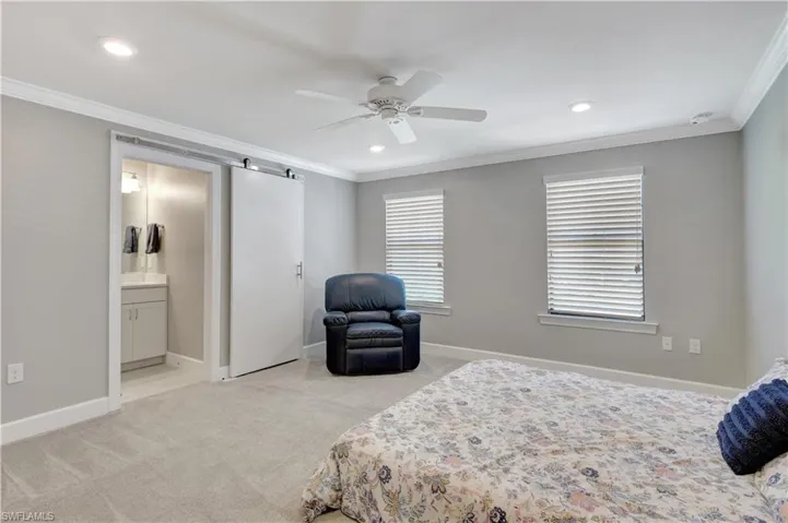 3rd Carpeted bedroom with ornamental molding, multiple windows, connected bathroom, and ceiling fan
