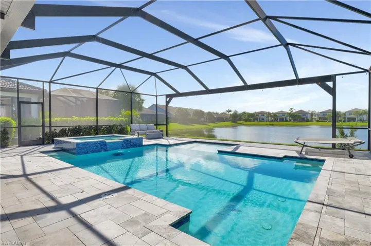 View of pool with a water view, a patio, a lanai, and an in ground hot tub