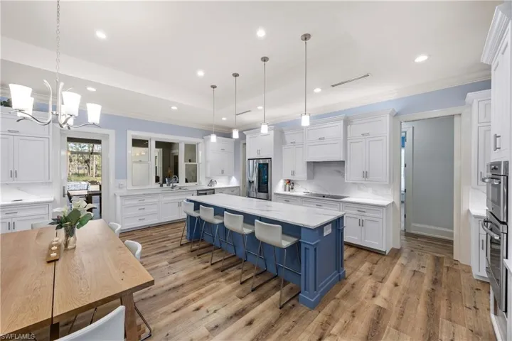 Open kitchen with Quartz countertops, seating at island and formal dining area.