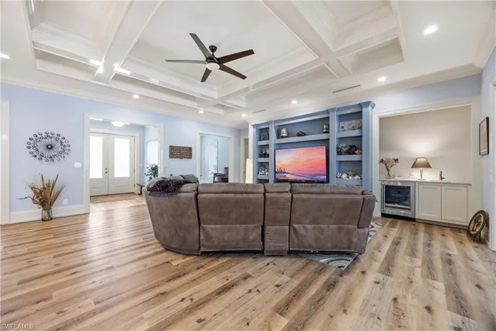 Front entrance into Great Room, featuring large sectional sofa, big screen TV, and bar with beverage refrigerator.