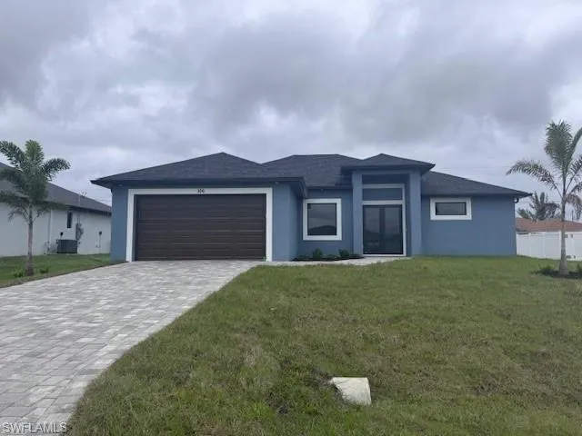 View of front facade featuring stucco siding, cooling unit, a front yard, a garage, and decorative driveway