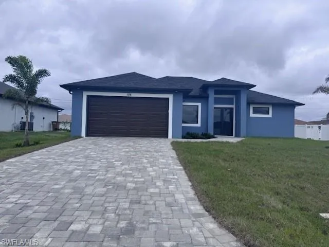 View of front of house with a garage, decorative driveway, a front lawn, and stucco siding