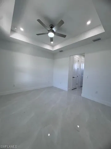 Unfurnished room featuring ceiling fan and a raised ceiling