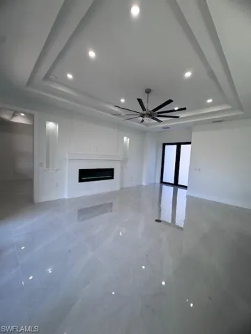 Unfurnished living room with ceiling fan and a tray ceiling