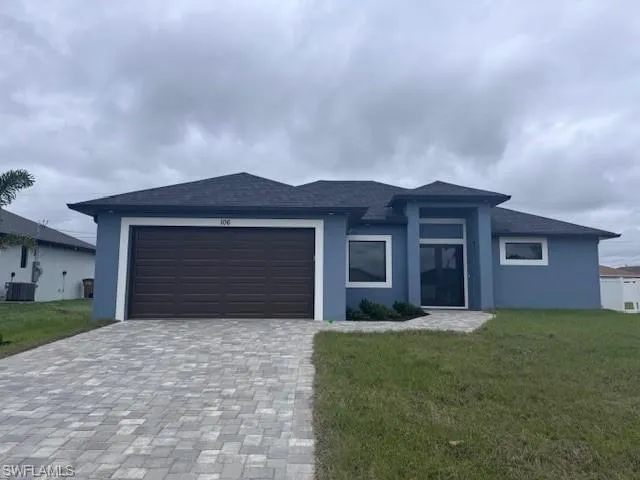 View of front of property featuring a garage, decorative driveway, a front yard, and stucco siding