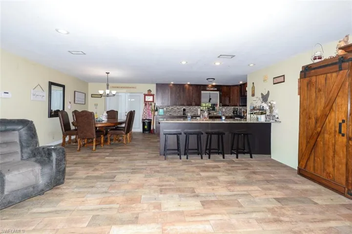 Kitchen with dark wood finish cabinets, a barn door, open floor plan, a kitchen bar, and a peninsula