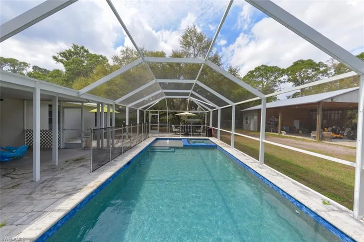 Combined pool / hot tub featuring a lanai, a patio, a lawn, and a sunroom