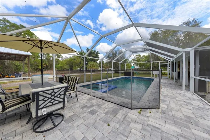 Integrated pool / hot tub with a sunroom, a patio area, glass enclosure, and outdoor dining space