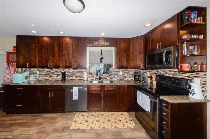 Kitchen featuring stainless steel appliances, open shelves, light stone counters, dark wood finish cabinetry, and recessed lighting