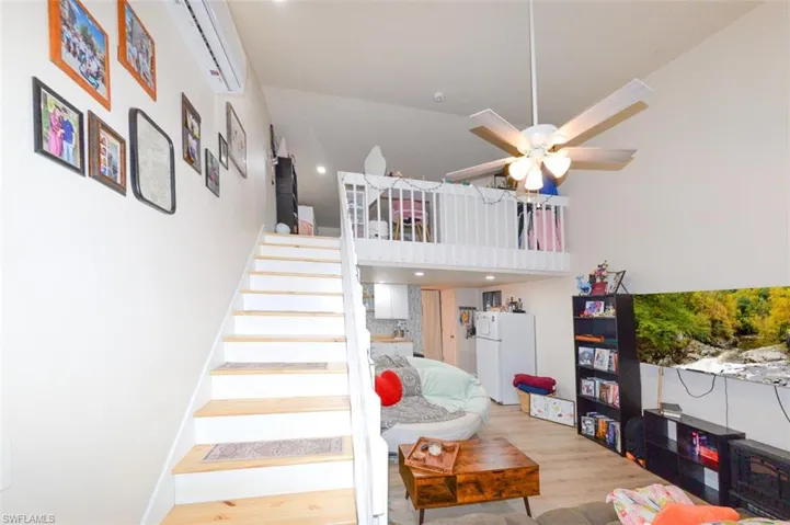 Stairs with a ceiling fan, wood finished floors, and a high ceiling