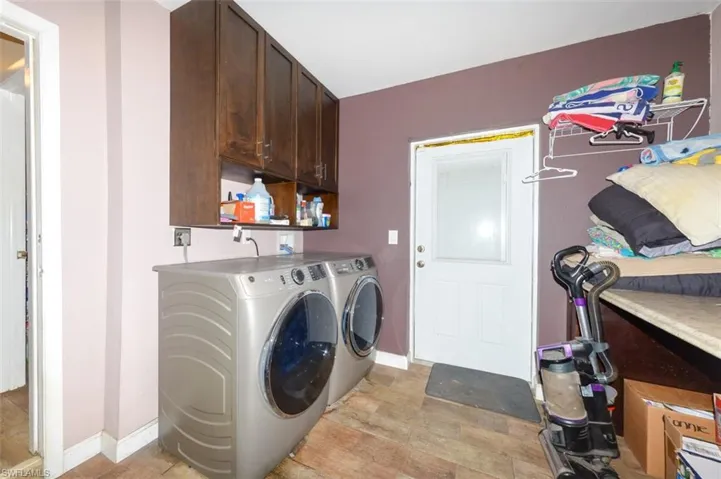 Laundry area featuring washer and dryer, light wood-style floors, and cabinet space