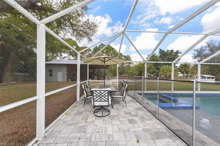 View of patio featuring a sunroom, outdoor dining space, a lanai, and a pool with connected hot tub
