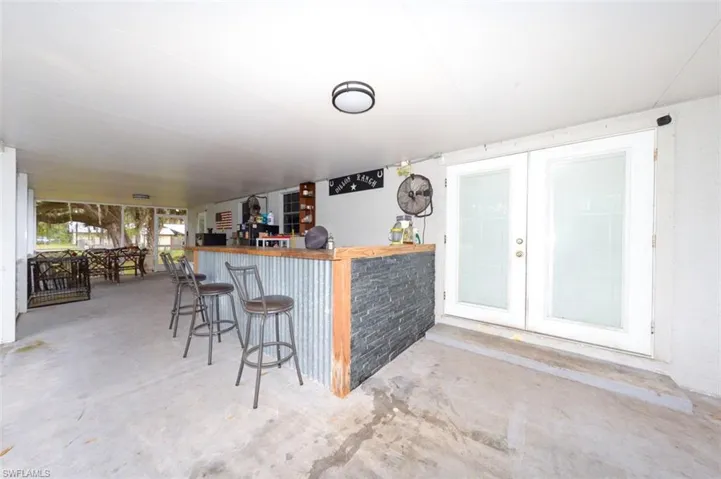 Indoor dry bar with concrete floors, butcher block counters, and french doors