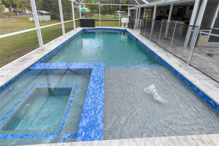 Integrated pool / spa with a sunroom, glass enclosure, and a lawn