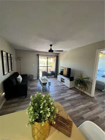 Living room featuring wood finished floors, a ceiling fan, and baseboards