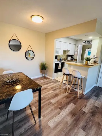 Kitchen featuring white appliances, white cabinets, light wood-style floors, and a peninsula