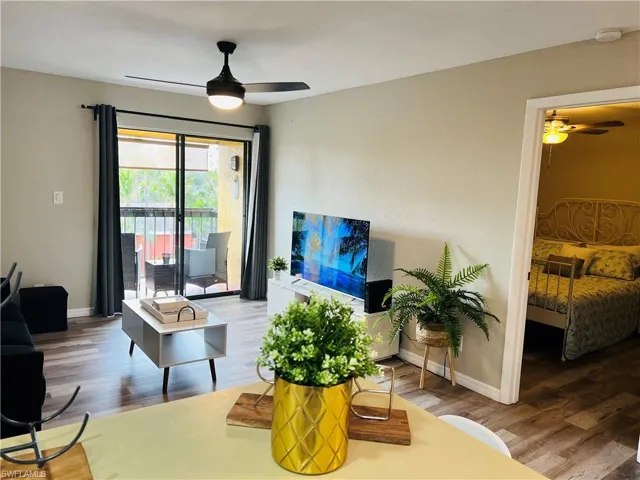 Living room with a ceiling fan, wood finished floors, and baseboards