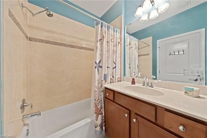 Full bathroom with visible vents, vanity, and shower / bathtub combination with curtain