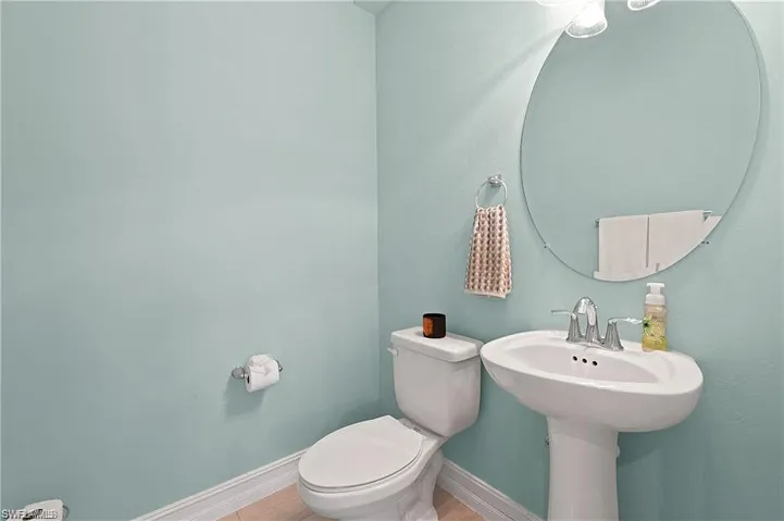 Half bathroom featuring baseboards, toilet, and a sink, located on main level.