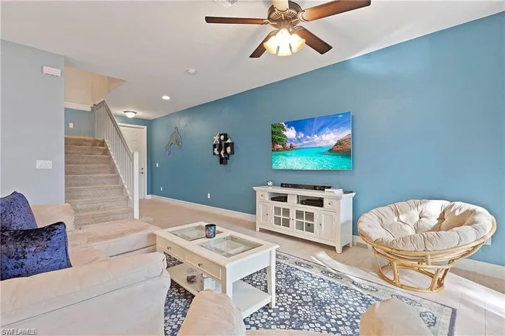Living room featuring baseboards, stairway, and ceiling fan