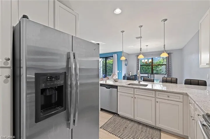 Kitchen featuring a sink, stainless steel appliances, a healthy amount of sunlight, and light stone counters