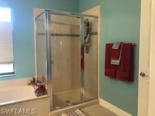 Bathroom with shower with separate bathtub and tile patterned floors