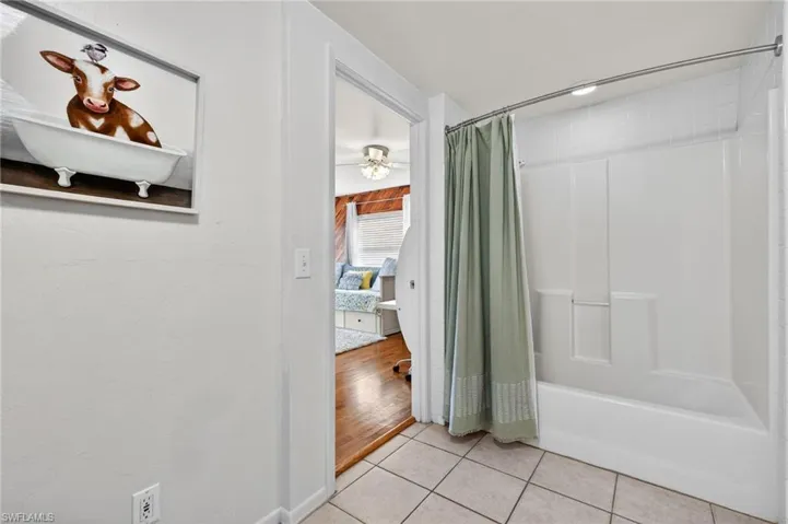 Ensuite bathroom featuring shower / bath combo, light tile patterned floors, and a ceiling fan