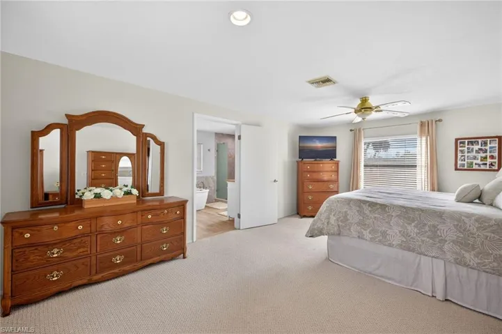 Bedroom featuring light colored carpet, a ceiling fan, ensuite bathroom, and recessed lighting