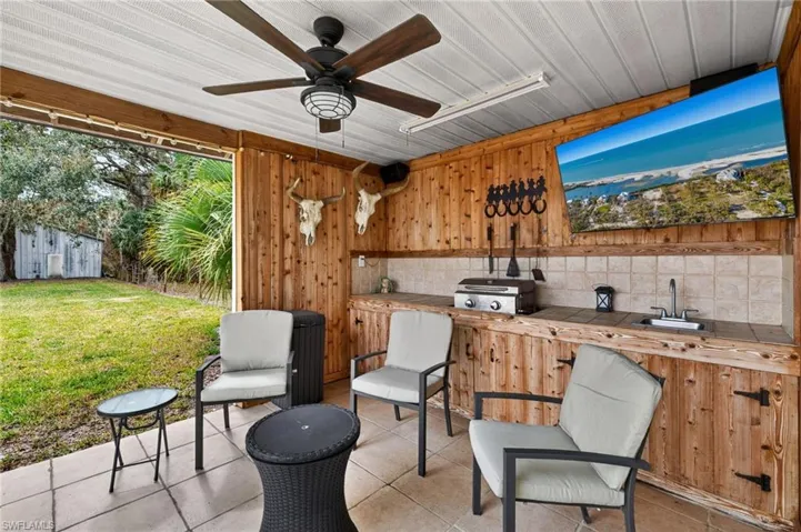 View of patio / terrace with a ceiling fan, a grill, exterior bar, and a storage unit