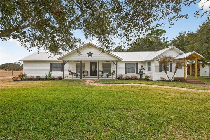 Single story home with a front lawn, a metal roof, ceiling fan, and a porch
