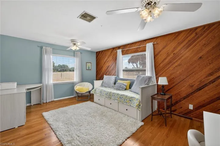 Bedroom featuring wood walls, ceiling fan, and light wood finished floors